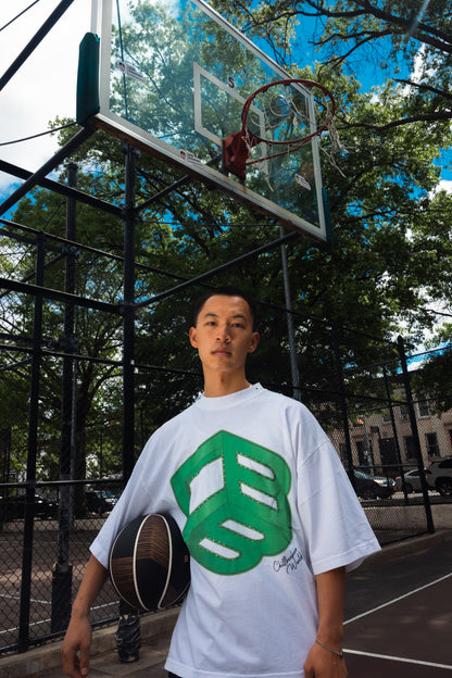 Model wearing white CHILLBAEBEEE Men's Tee with green CBB logo on an outdoor basketball court